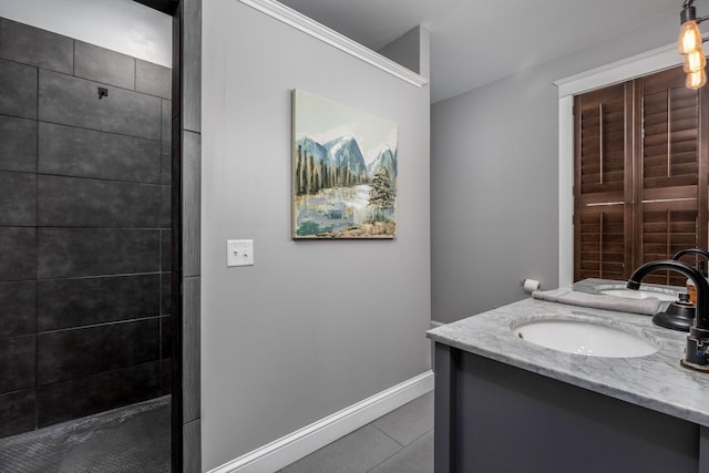 bathroom featuring tiled shower, vanity, and baseboards