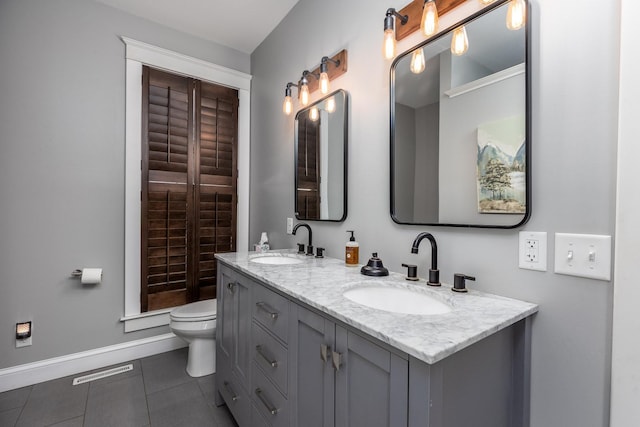 full bathroom with double vanity, tile patterned flooring, a sink, and toilet