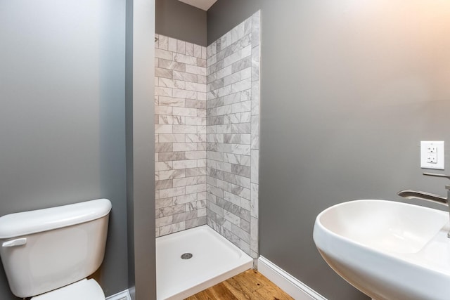 full bathroom featuring baseboards, toilet, wood finished floors, a shower stall, and a sink