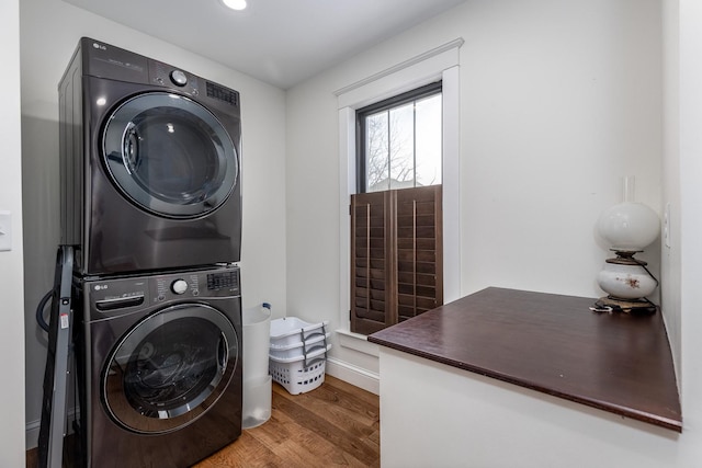 laundry room featuring stacked washer and dryer and wood finished floors