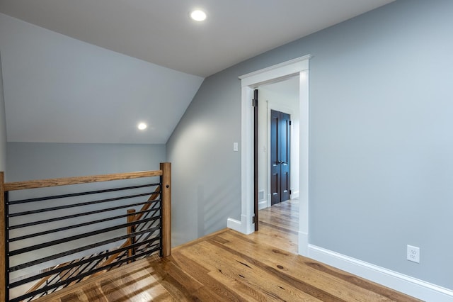 hall with recessed lighting, vaulted ceiling, an upstairs landing, wood finished floors, and baseboards