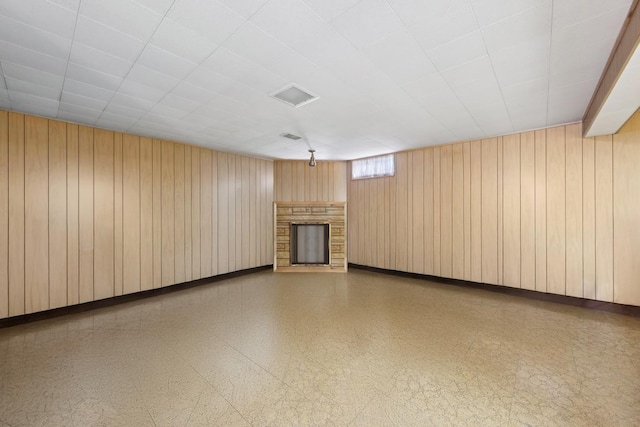 unfurnished living room with wooden walls, a fireplace, and tile patterned floors