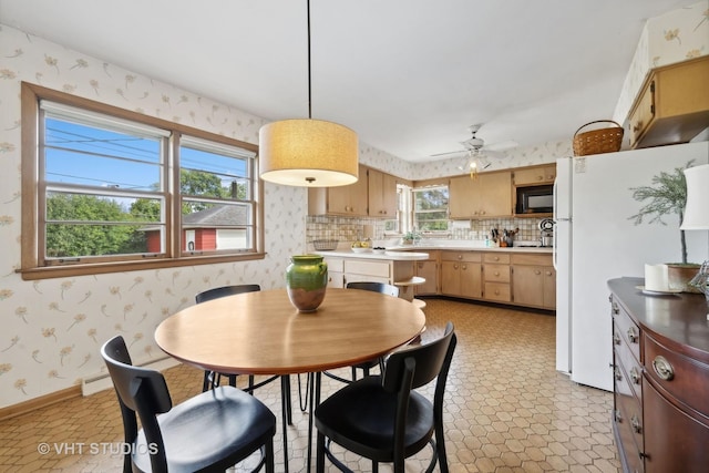 dining space featuring baseboards, light floors, ceiling fan, and wallpapered walls