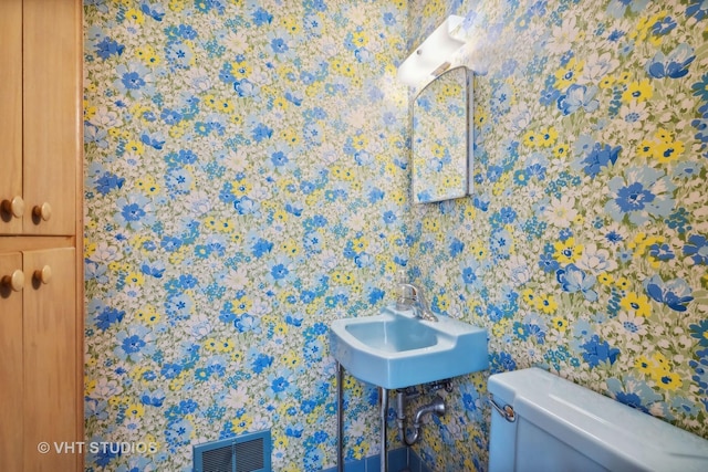 bathroom with toilet, visible vents, and a sink