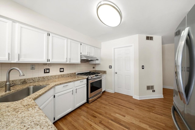 kitchen featuring under cabinet range hood, appliances with stainless steel finishes, white cabinets, and a sink