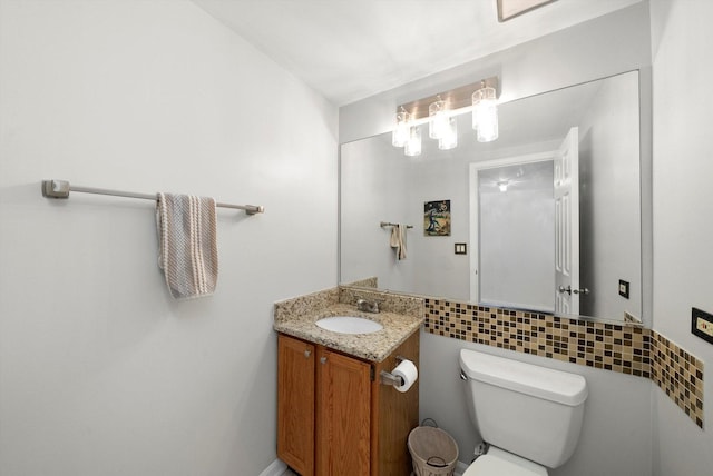 bathroom with toilet, backsplash, vanity, and tile walls