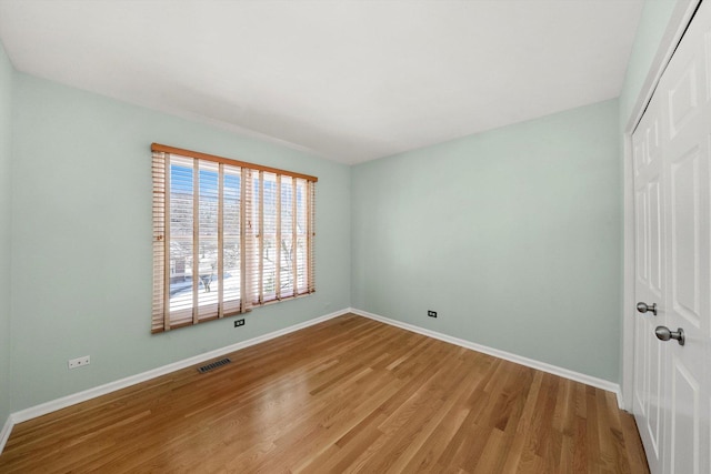 unfurnished bedroom with baseboards, visible vents, a closet, and wood finished floors