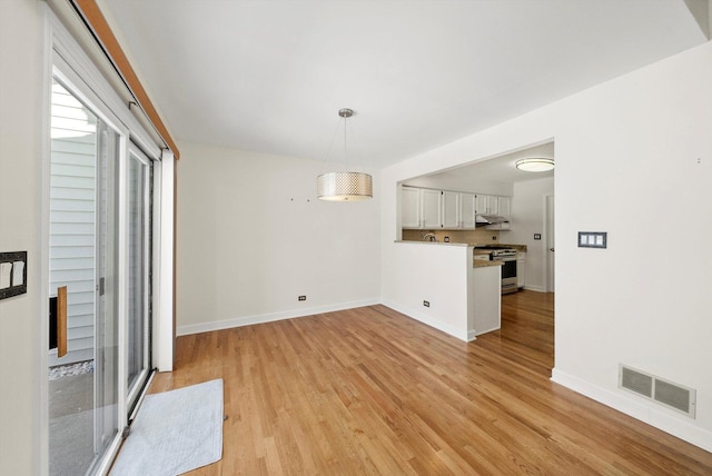 unfurnished dining area with light wood-type flooring, visible vents, and baseboards