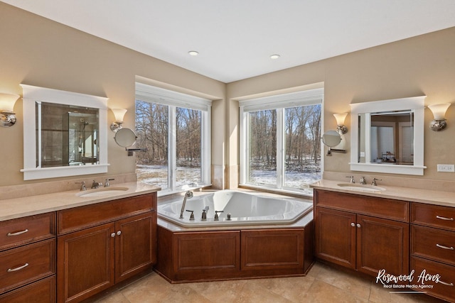 full bath featuring a garden tub, two vanities, and a sink