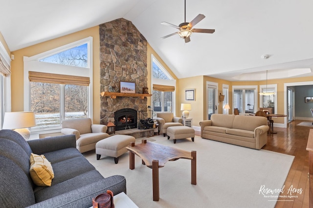 living room featuring high vaulted ceiling, a fireplace, wood finished floors, a ceiling fan, and baseboards