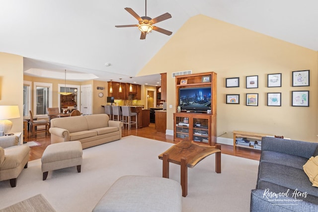 living area featuring visible vents, high vaulted ceiling, light wood-style flooring, and a ceiling fan