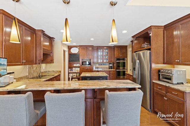 kitchen featuring stainless steel appliances, hanging light fixtures, brown cabinetry, glass insert cabinets, and a peninsula