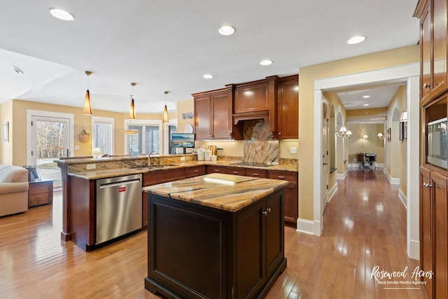 kitchen with a center island, pendant lighting, a sink, dishwasher, and a peninsula