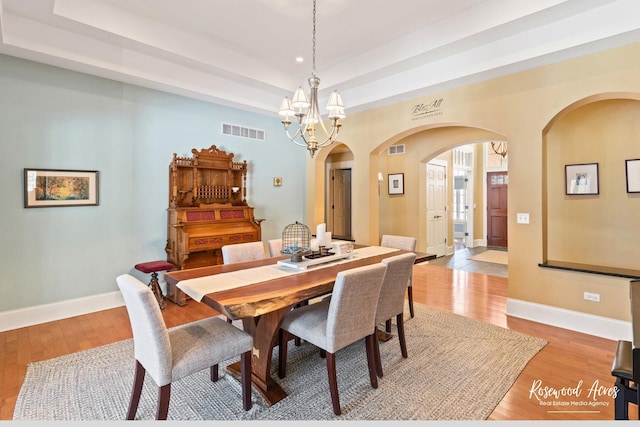 dining area featuring a tray ceiling, visible vents, light wood-style flooring, and baseboards