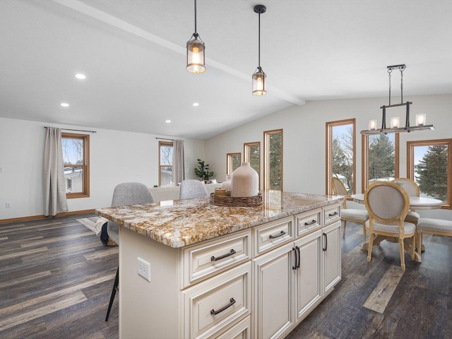 kitchen featuring pendant lighting, a breakfast bar, light stone counters, and a center island