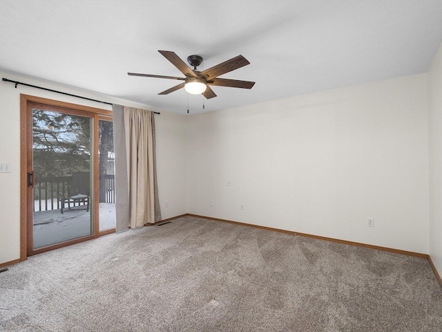 carpeted spare room featuring ceiling fan and baseboards