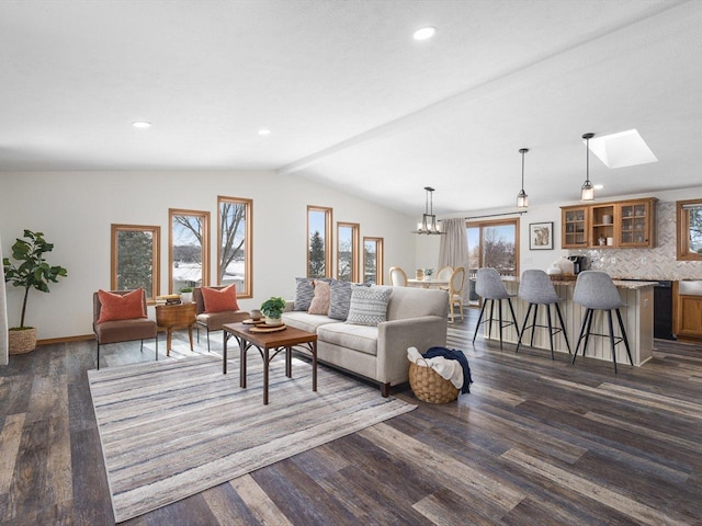 living room featuring vaulted ceiling with skylight, dark wood-style flooring, recessed lighting, and an inviting chandelier