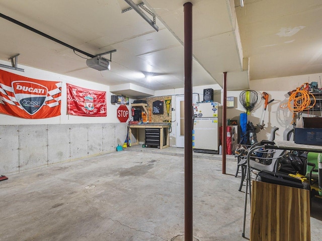 garage featuring freestanding refrigerator, a workshop area, and a garage door opener