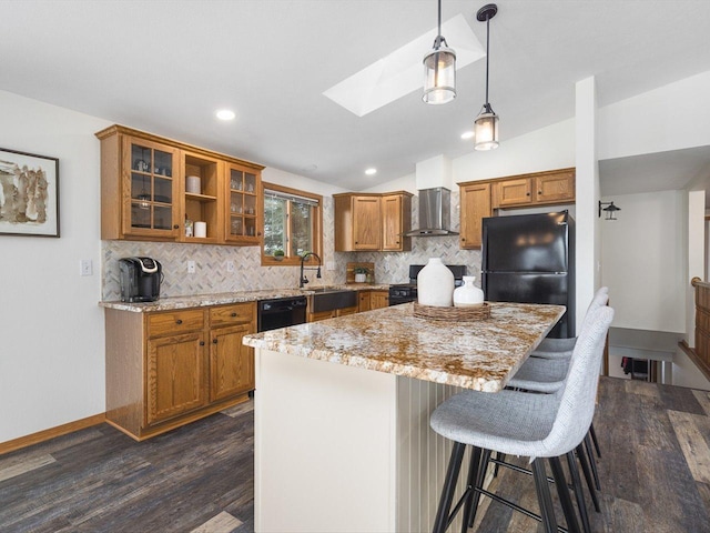 kitchen with glass insert cabinets, a breakfast bar, a center island, black appliances, and pendant lighting