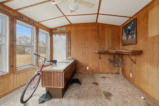 home office with lofted ceiling, wood walls, and a ceiling fan