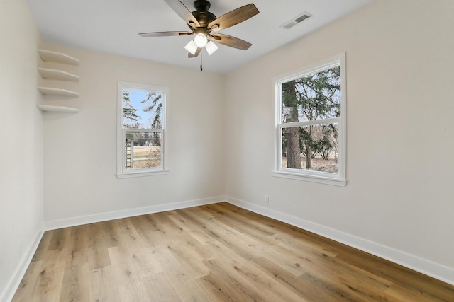 unfurnished room featuring a wealth of natural light, visible vents, and baseboards