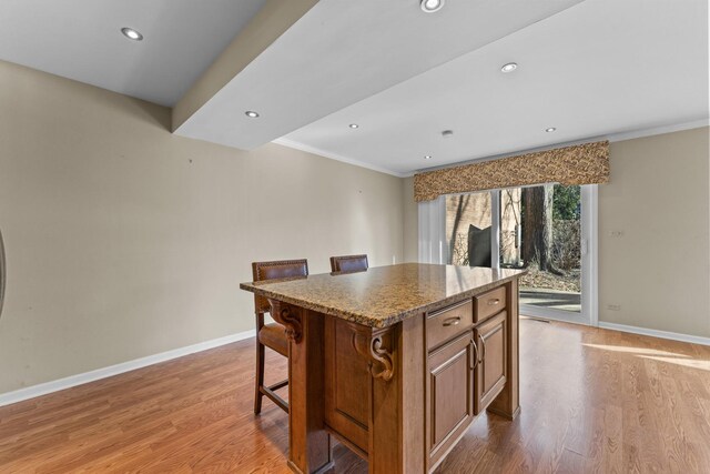 kitchen with brown cabinetry, a center island, baseboards, and wood finished floors