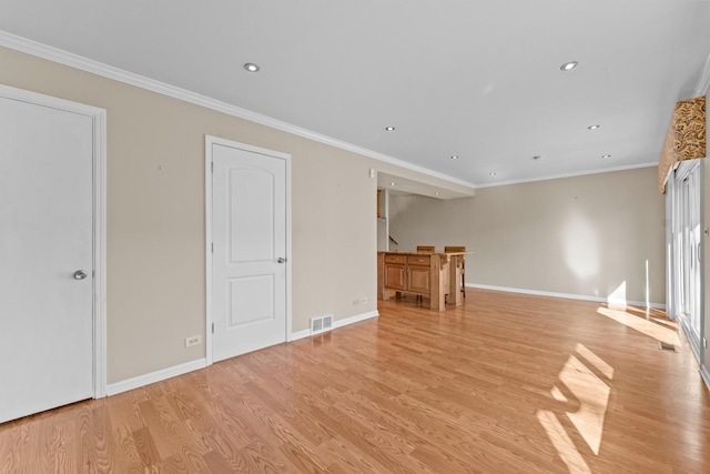 unfurnished living room with baseboards, light wood-style floors, visible vents, and ornamental molding