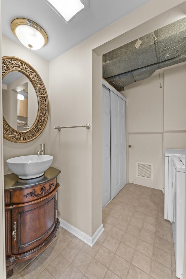 bathroom with visible vents, baseboards, vanity, and washer and clothes dryer