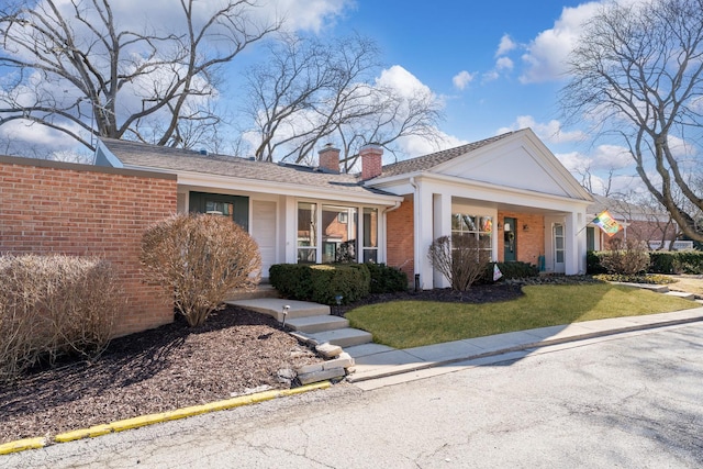 view of front of property with a front lawn, brick siding, and a chimney