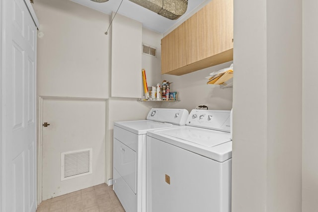 laundry room with washing machine and clothes dryer, visible vents, and cabinet space