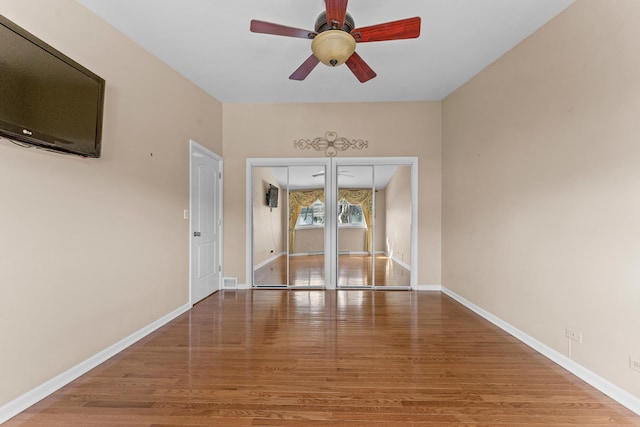 empty room with a ceiling fan, baseboards, and wood finished floors