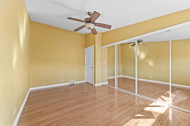 unfurnished bedroom with visible vents, wood finished floors, a closet, baseboards, and ceiling fan