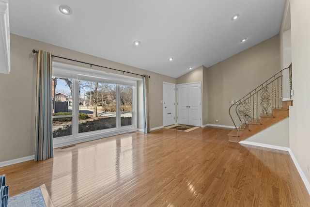 unfurnished living room featuring vaulted ceiling, baseboards, visible vents, and wood finished floors