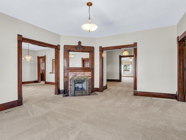 unfurnished living room featuring a fireplace, visible vents, light carpet, a textured ceiling, and baseboards