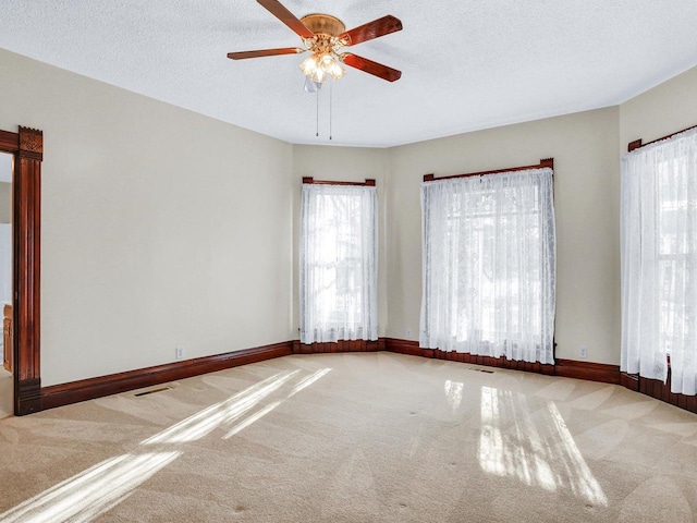 spare room with visible vents, light carpet, and a textured ceiling