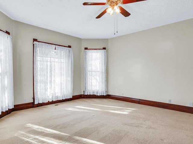 unfurnished room with carpet, ceiling fan, a textured ceiling, and baseboards