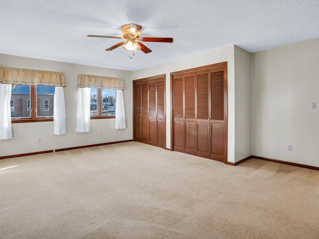 unfurnished bedroom featuring multiple closets, light colored carpet, and baseboards