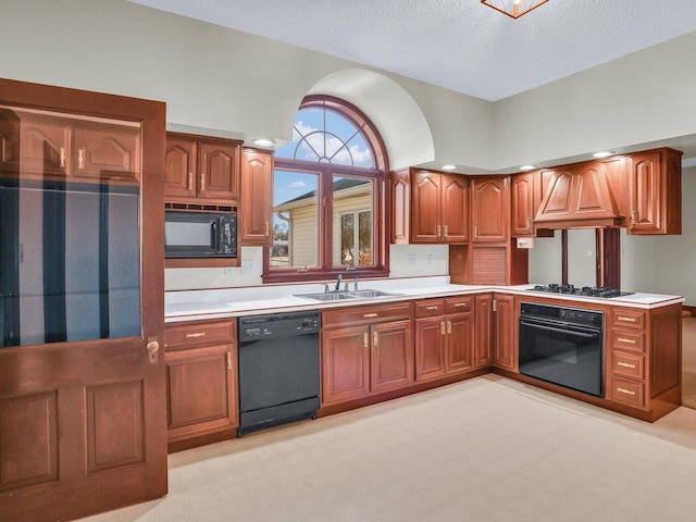 kitchen featuring light countertops, brown cabinetry, a sink, premium range hood, and black appliances