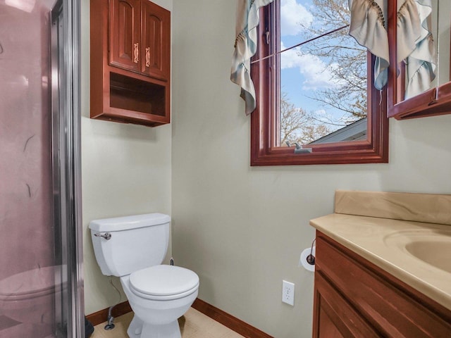 bathroom with toilet, vanity, and baseboards