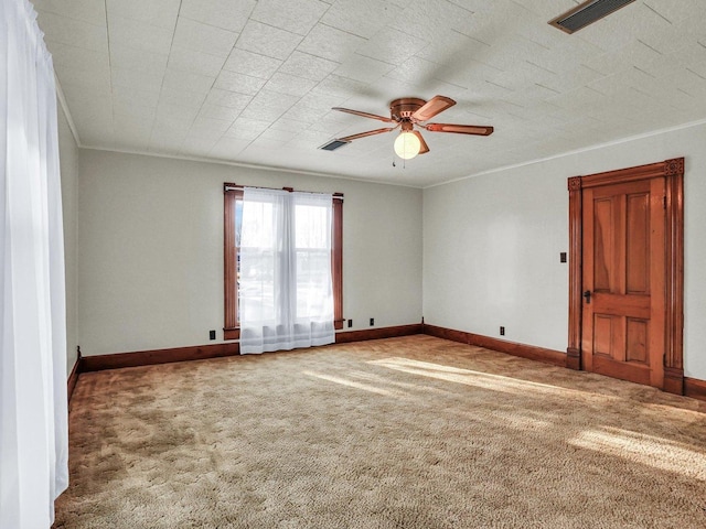 spare room featuring carpet, visible vents, ornamental molding, ceiling fan, and baseboards