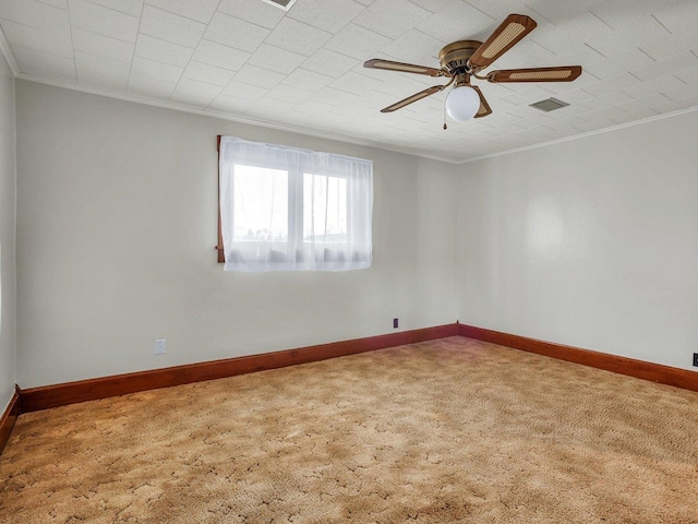 empty room featuring crown molding, visible vents, a ceiling fan, carpet flooring, and baseboards