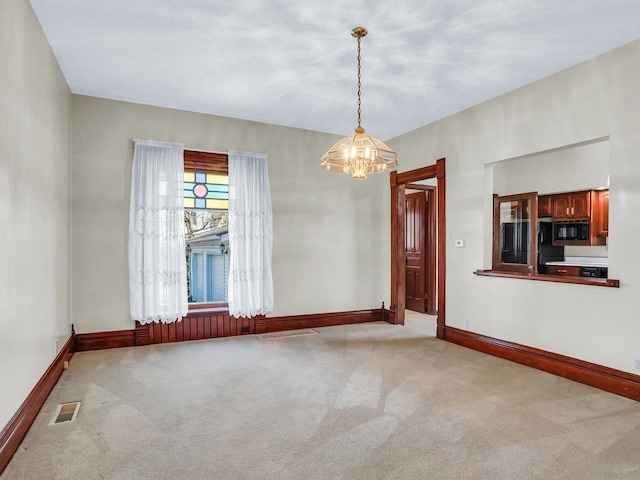 spare room featuring light colored carpet and baseboards