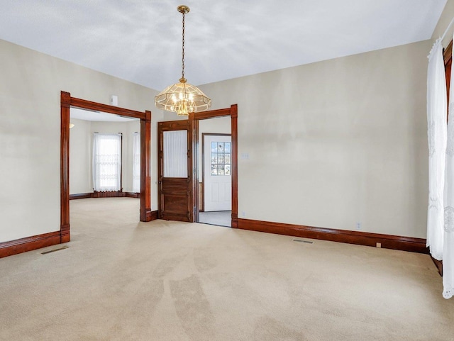 carpeted spare room with an inviting chandelier, baseboards, and visible vents