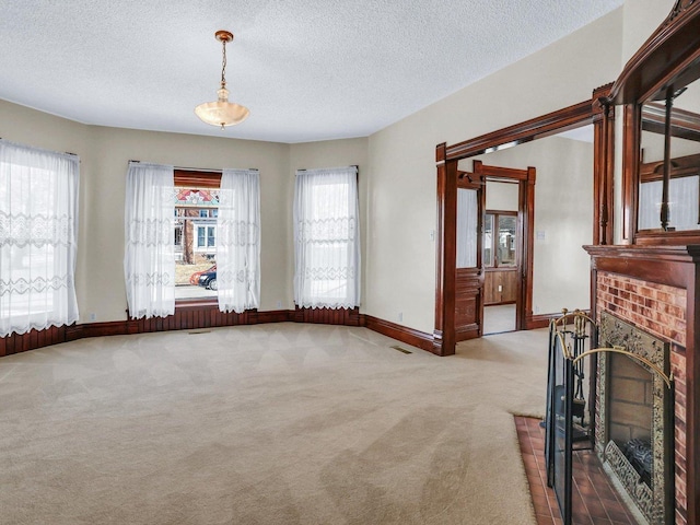 unfurnished living room featuring a brick fireplace, baseboards, visible vents, and light colored carpet