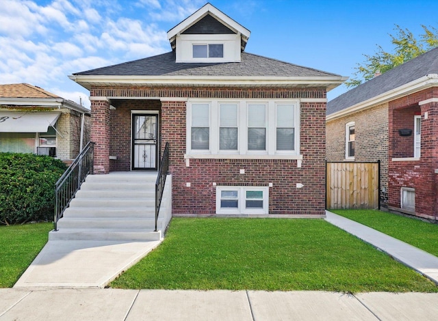 bungalow featuring a front yard, brick siding, and roof with shingles