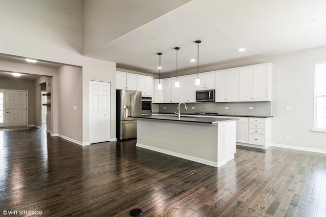 kitchen featuring a sink, dark countertops, dark wood finished floors, and stainless steel appliances