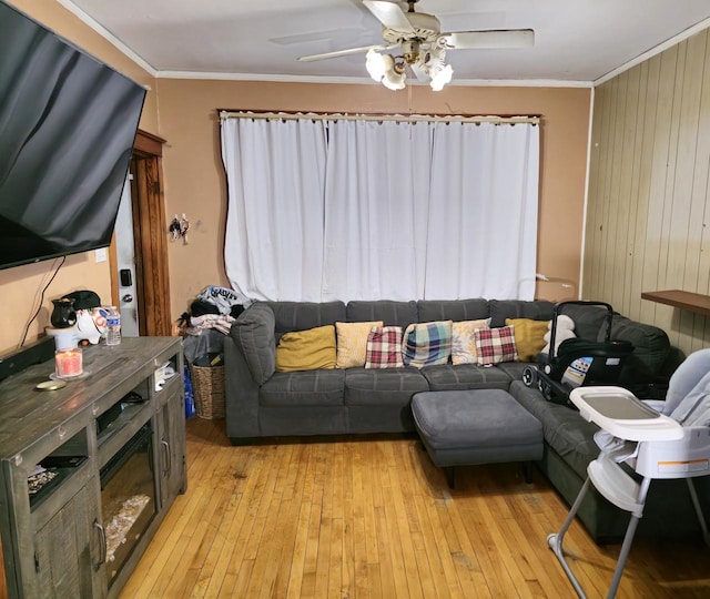 living area featuring ornamental molding, light wood-type flooring, and ceiling fan