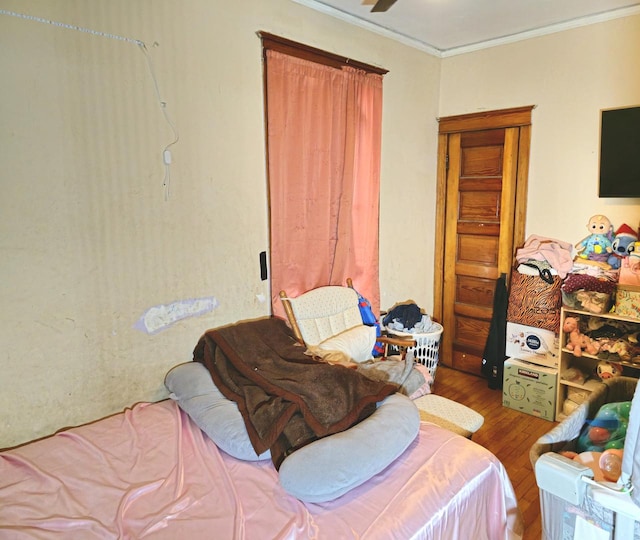 bedroom with ornamental molding and wood finished floors