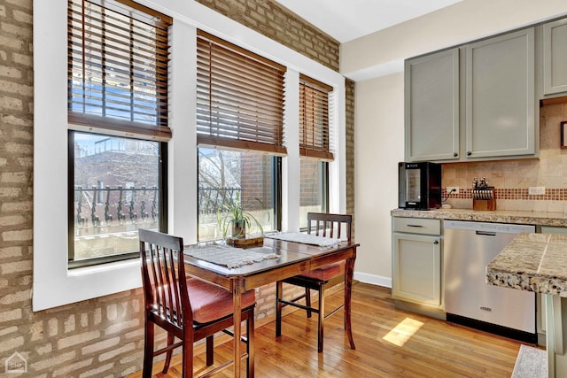 dining space featuring brick wall, light wood-type flooring, a mountain view, and baseboards