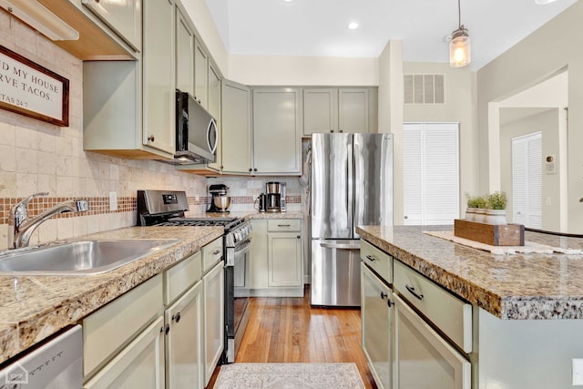 kitchen featuring visible vents, decorative backsplash, appliances with stainless steel finishes, hanging light fixtures, and a sink